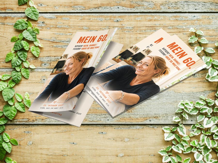 Mock-up einer vierseitigen DIN-lang-Einladung zum 60. Geburtstag mit natürlichem Handyfoto, markanter Typografie und modernem Gestaltungskonzept auf einer Holzoberfläche.